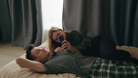 couple relaxing on bed using smartphone
