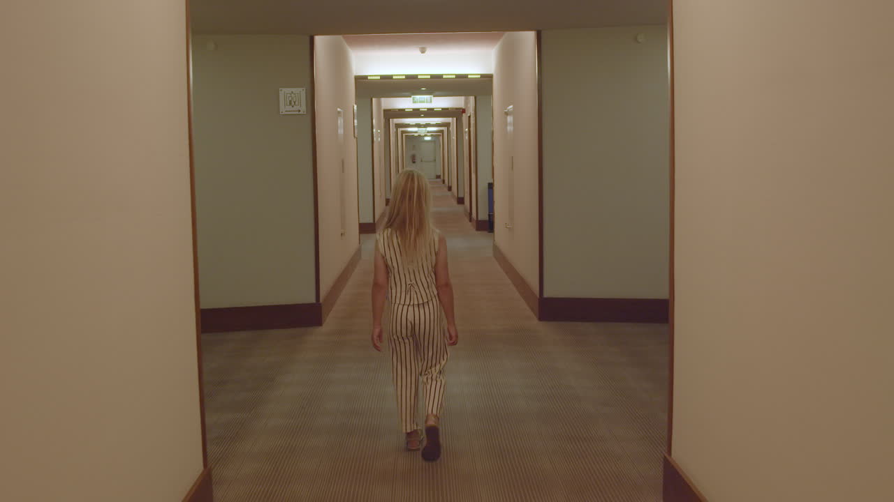 una chica caminando por el corredor de un hotel.