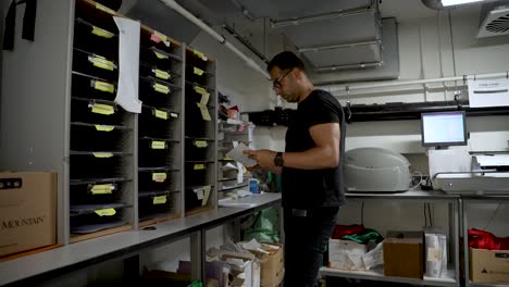 european male with an athletic build sorting mail in a post room