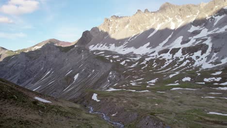 imágenes aéreas de drones que se desplazan lentamente a través de un espectacular paisaje montañoso irregular con parches residuales de nieve y praderas alpinas en suiza