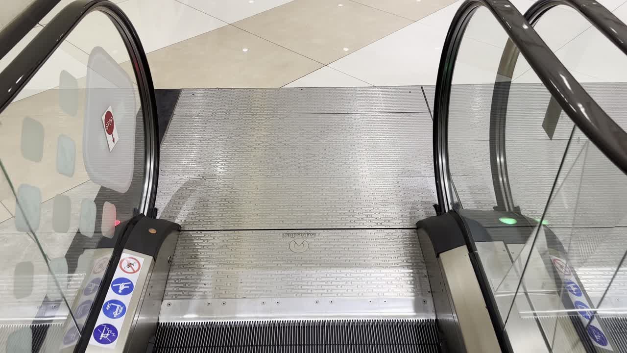 pov shot of going down on escalator with escalator safety warning
