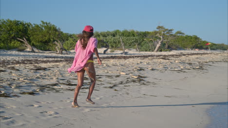 thin latin girl in a bikini and a shirt running on the beach enjoying her self on a sunny day