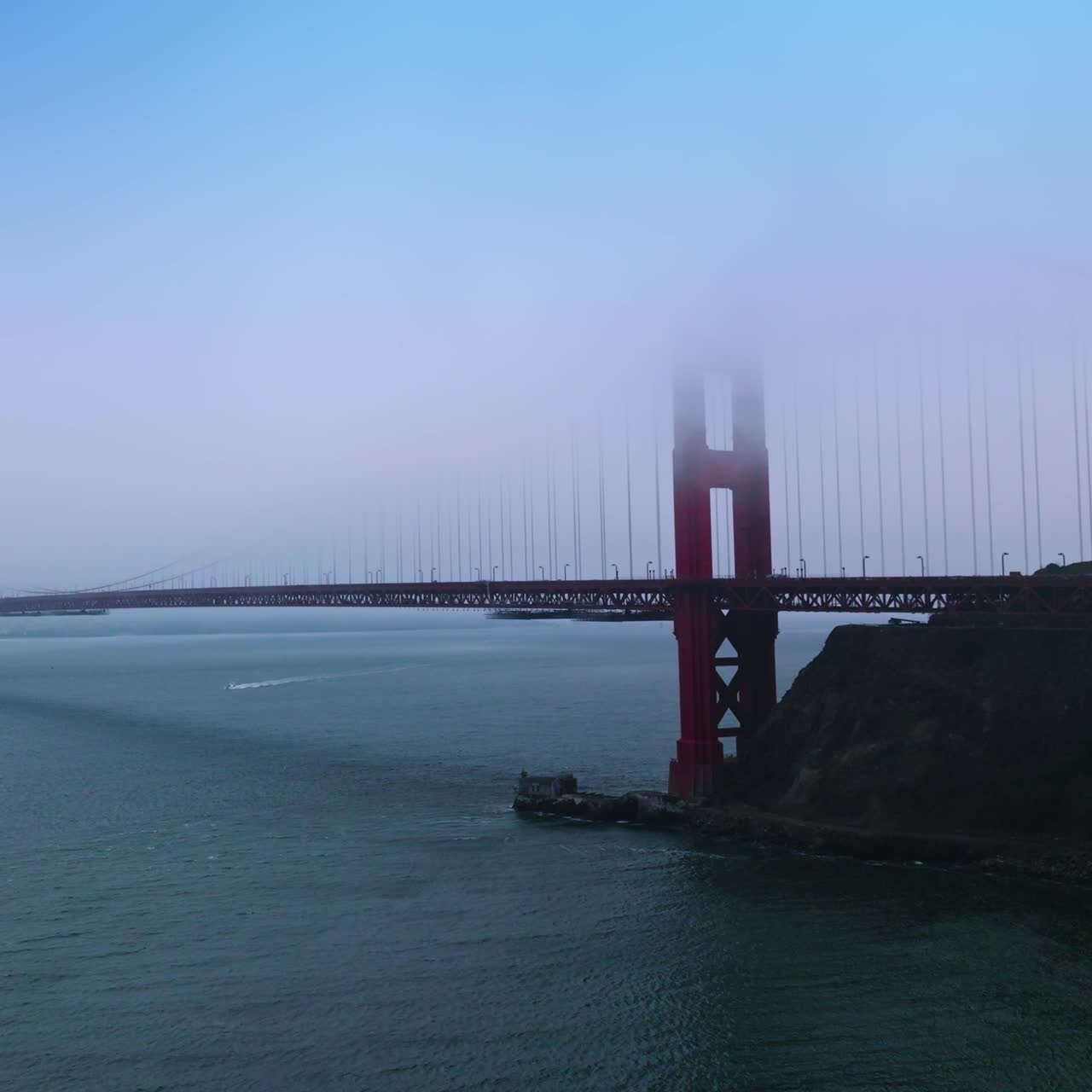 Amazing Golden Gate Bridge in San Francisco over the Pacific ocean bay. The tops of the bridge aren't seen in the fog