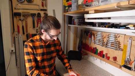 young caucasian hipster wears protection glasses while working in home garage