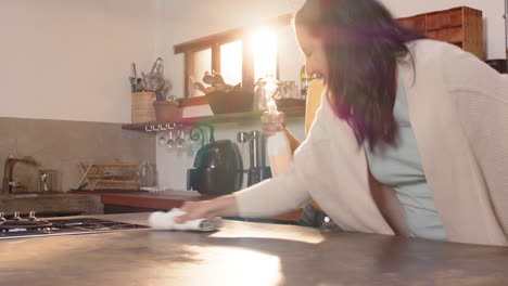 cleaning kitchen counter together, multiracial young woman and grandmother smiling, at home