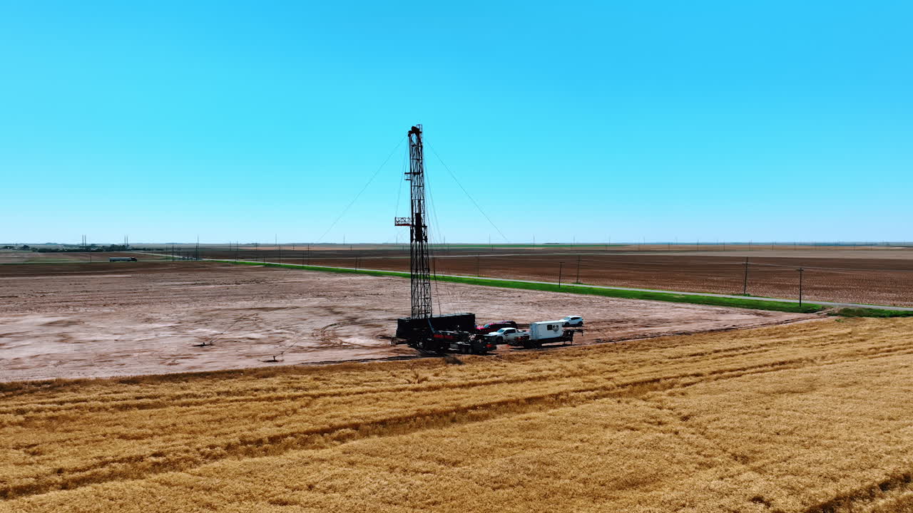 Distancing from the oil rig site in the deserted area. Few trucks with equipment for drilling resources from aerial view.
