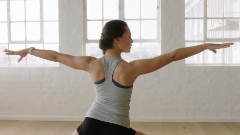 healthy yoga woman practicing warrior pose enjoying fitness lifestyle exercising in workout studio stretching training on exercise mat at sunrise