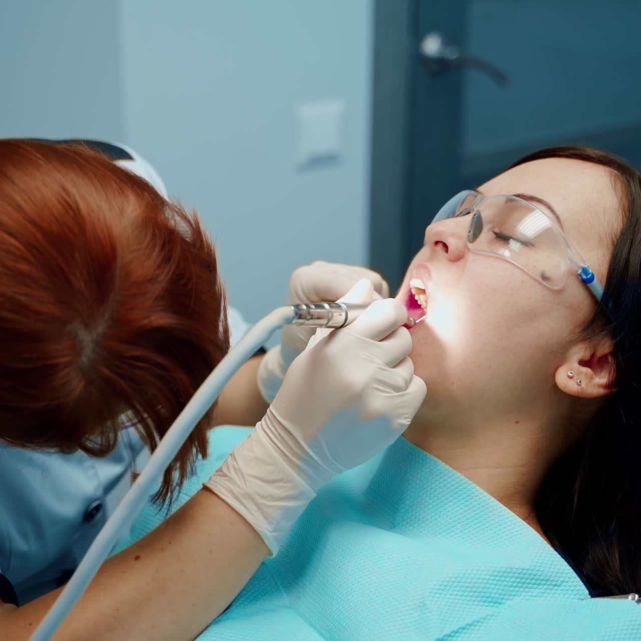 . Patient sitting on dentist chair. Dentist in uniform perform dental operation on patient