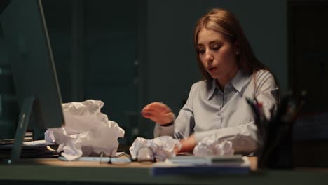 stressed businesswoman working late with crumpled papers