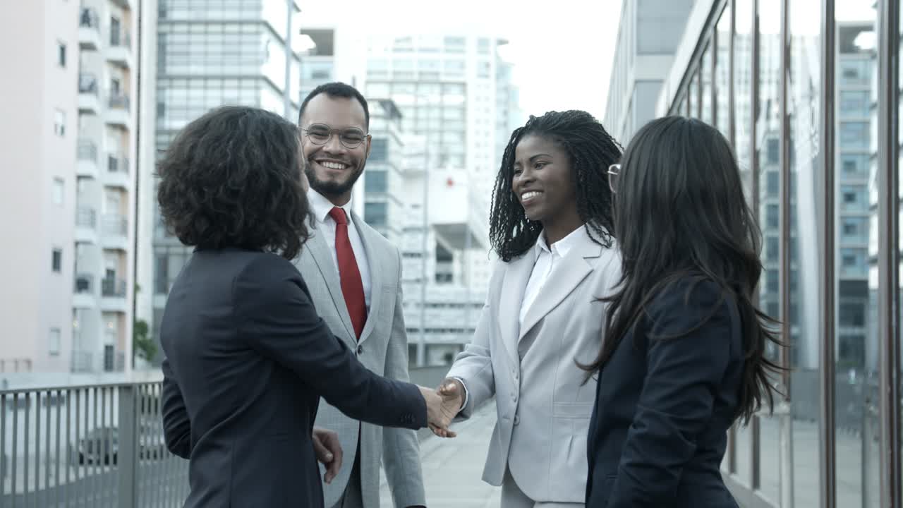 Cheerful managers meeting on street and shaking hands