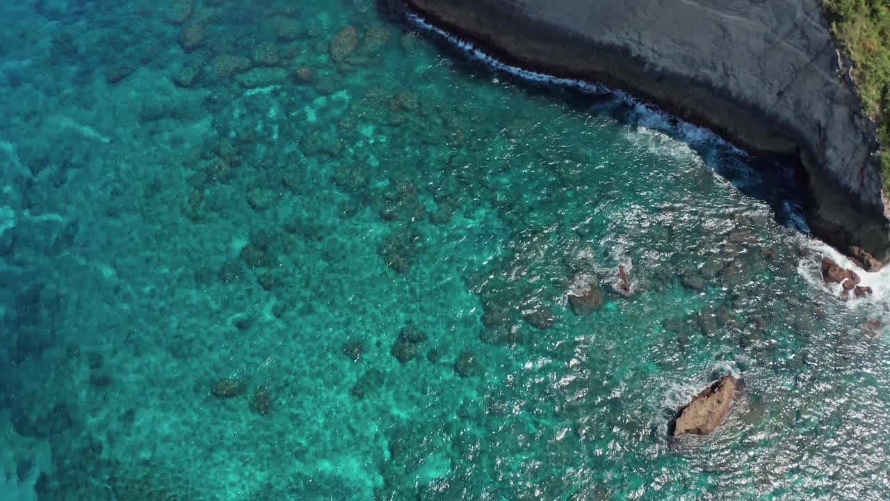 Aerial shot of Atuh Beach (Pantai Atuh) and its Natural arch formation that rises above the crystal-clear, turquoise-blue waters on Nusa Penida Island, Bali, Indonesia