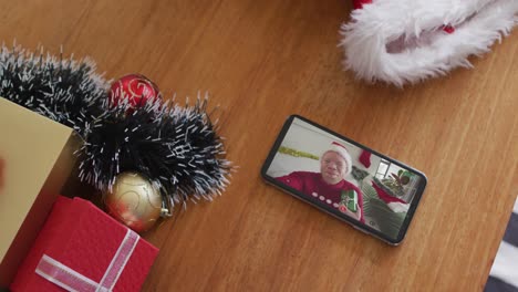 Un-Hombre-Afroamericano-Albino-Sonriente-Con-Sombrero-De-Papá-Noel-En-Una-Videollamada-Navideña-En-Un-Teléfono-Inteligente