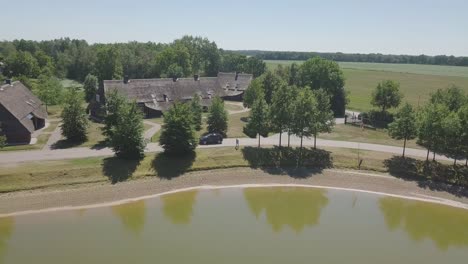 Panoramic-aerial-view-of-a-dark-blue-car-driving-around-a-lake-in-the-Netherlands