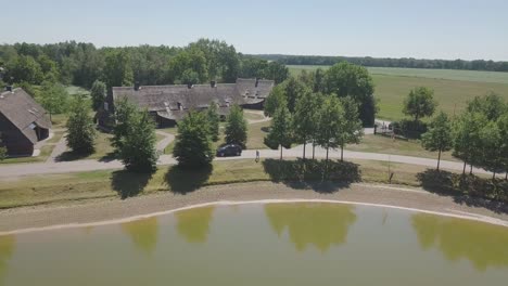 panoramic aerial view of a dark blue car driving around a lake in the netherlands