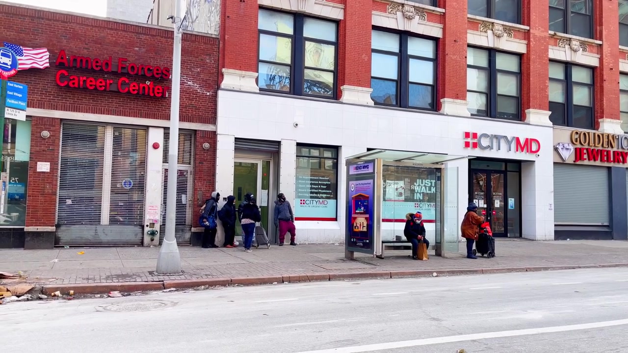 New York, USA, 9 marzo 2022: Pedoni fuori dalla vetrina di CityMD su Harlem Street. I pedoni aspettano vicino alle vetrine di CityMD, di gioiellerie e di ottici su un marciapiede di New York.