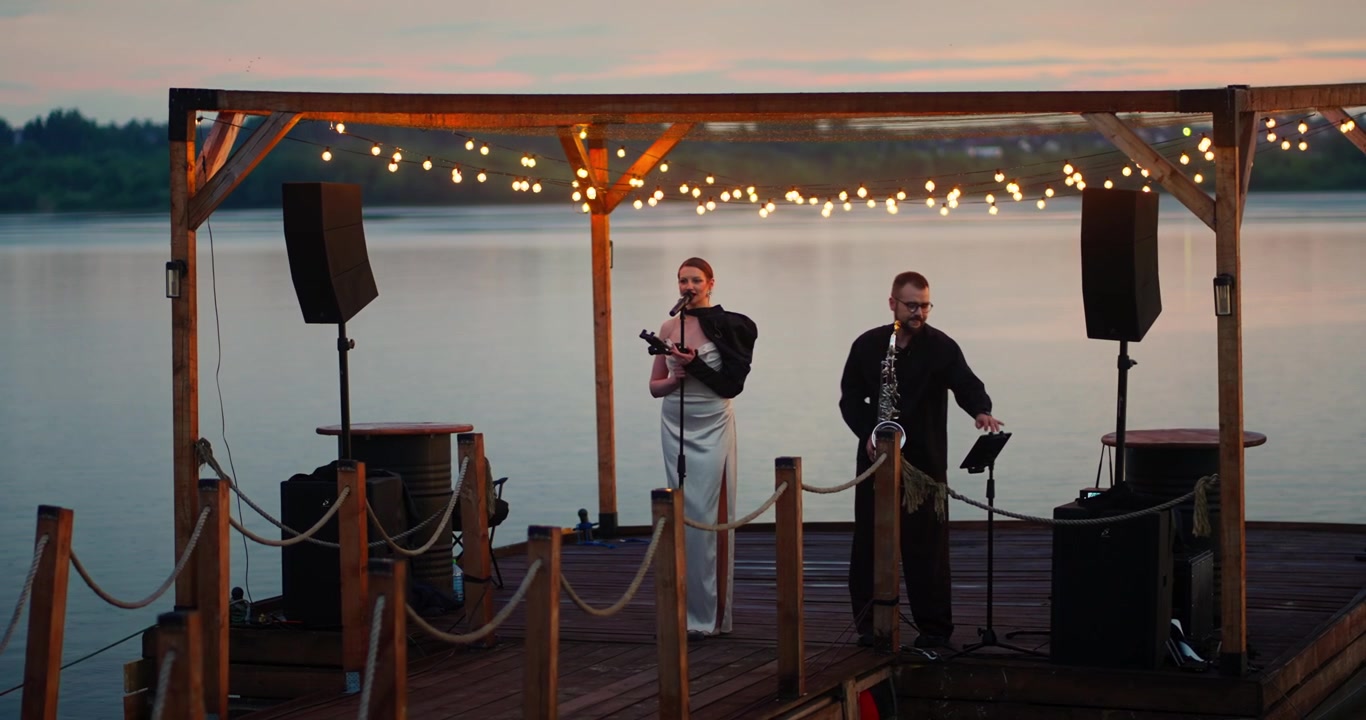 Duo Performing Music on a Wooden Pier at Sunset