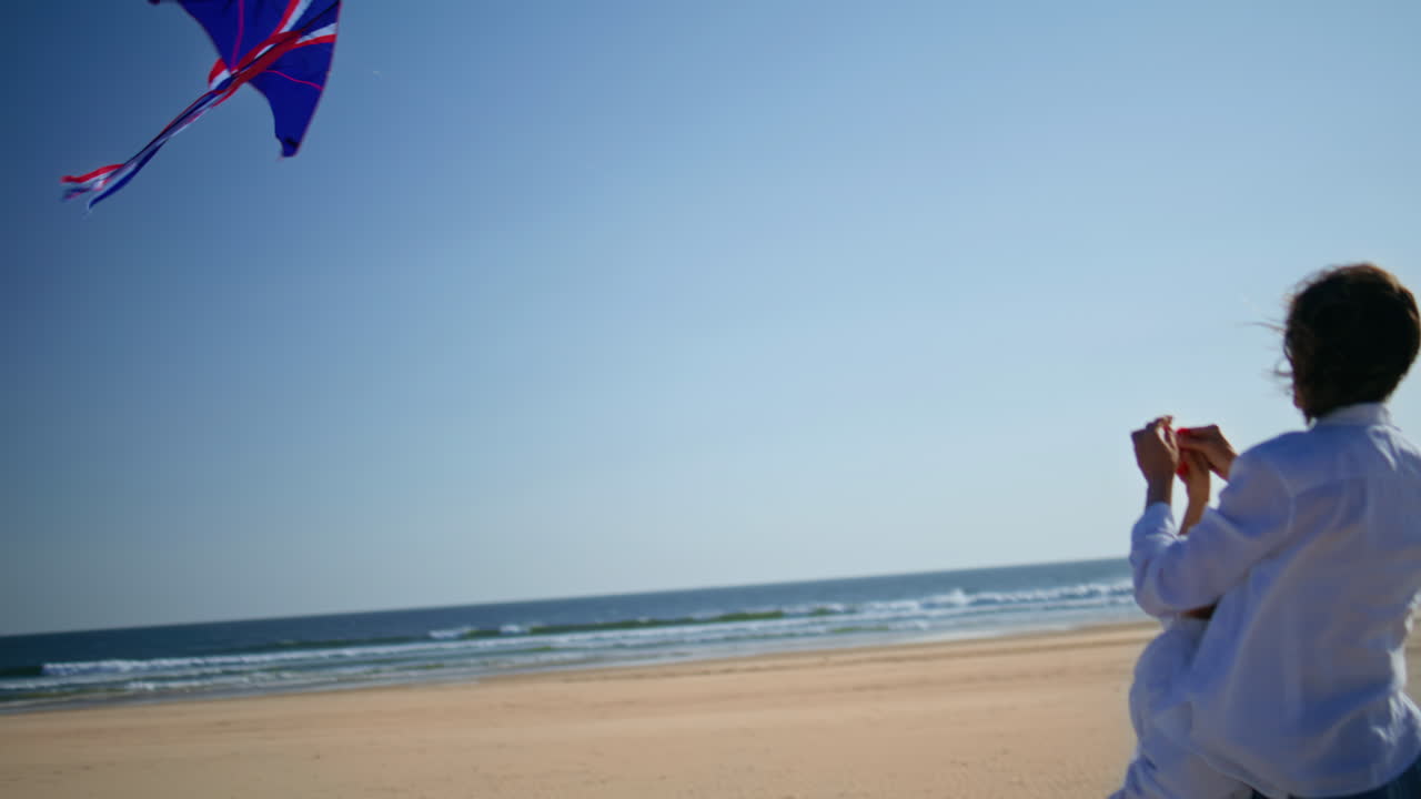 Mother child flying kite together on sandy beach. Family enjoying active leisure