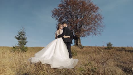 newlyweds. caucasian groom with bride near beautiful autumn tree. wedding couple