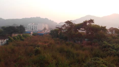 Mira-road-green-ground-under-construction-buildings-and-mountains-drone-shot-bird's-eye-view