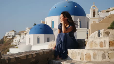 woman in blue dress admiring the view in santorini, greece