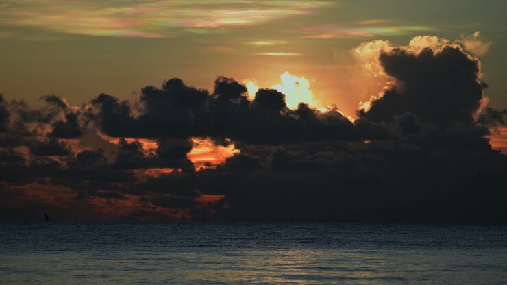 Hermosa toma de lapso de tiempo del sol naranja saliendo sobre el océano y abriéndose paso entre las nubes desde la costa de Tanzania