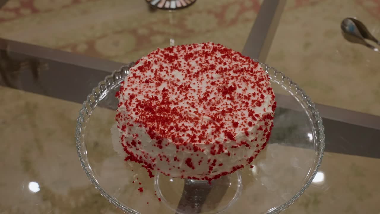 Deliciosa tarta red velvet cubierta con glaseado de queso crema y migas rojas sobre un elegante soporte de cristal