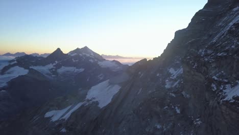 Amplia-Vista-Aérea-Desde-Drones-Sobre-Los-Alpes-Al-Amanecer-Con-Picos-Montañosos,-Laderas-Y-Nieve