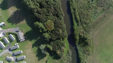 antena de arriba hacia abajo de un río y el borde de un parque de caravanas de vacaciones