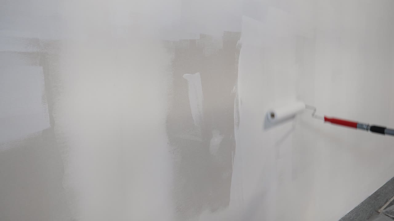 pintor aplicando una capa de imprimación de pintura blanca a paneles de yeso con rodillo