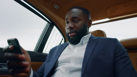 Closeup-african-man-holding-phone-at-backseat.-Man-having-video-call-at-car