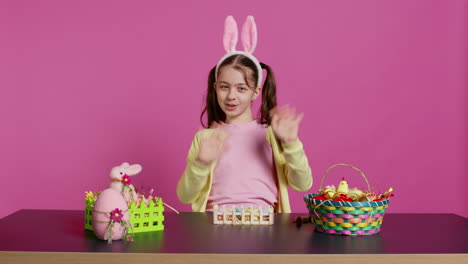 energetic young girl with adorable bunny ears waving in studio