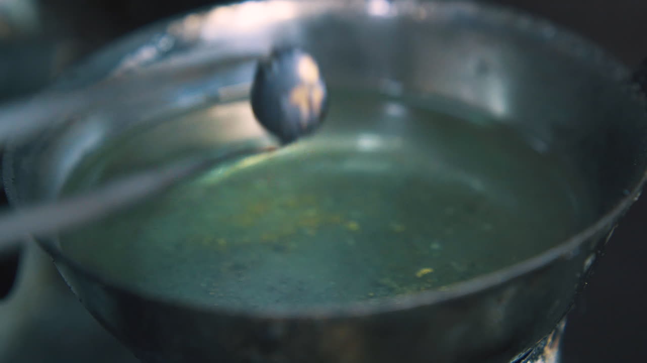 gioielliere mette una goccia di metallo in una tazza con liquido in negozio da vicino
