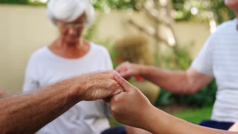 Senior-friends-holding-hands-and-meditating-in-garden-4k