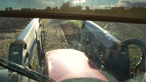 view through a dirty windshield of a tractor, while driving on a field for plowing