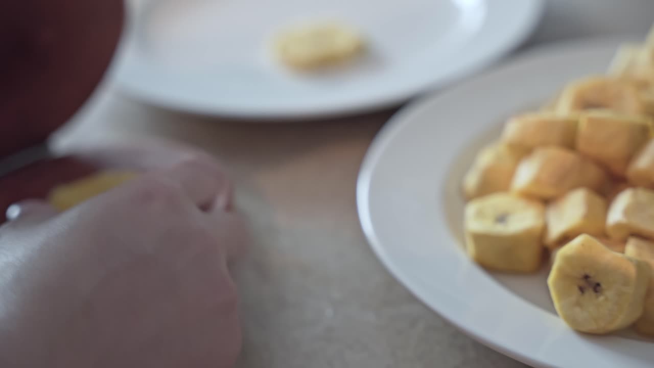 las manos usan una herramienta de madera para machacar y convertir los trozos de plátano en sabrosos chips