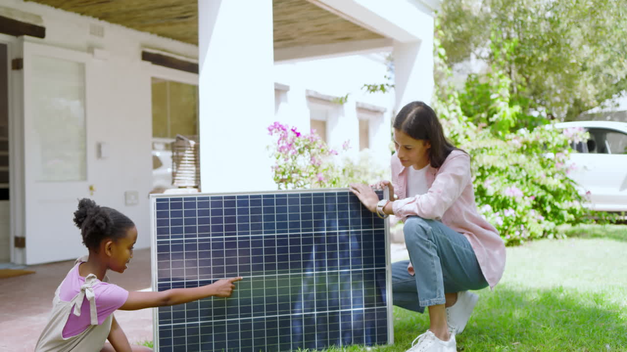 Mother and daughter exploring solar panel technology together in sunny backyard