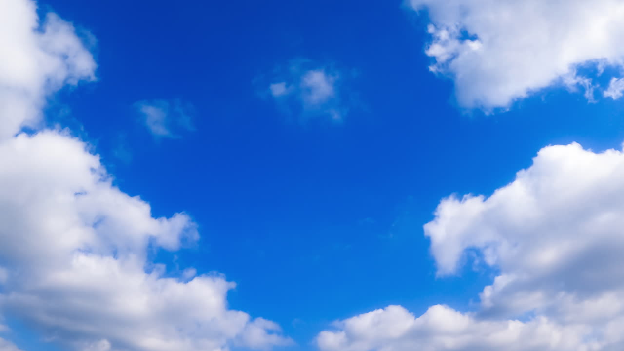 Fluffy white clouds fly in the atmosphere. Lovely azure sky at backdrop. Low angle view. Timelapse.