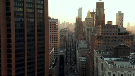 Fly-above-wide-and-busy-Park-Avenue-surrounded-by-high-rise-buildings.-Office-towers-against-sunset.-Manhattan,-New-York-City,-USA