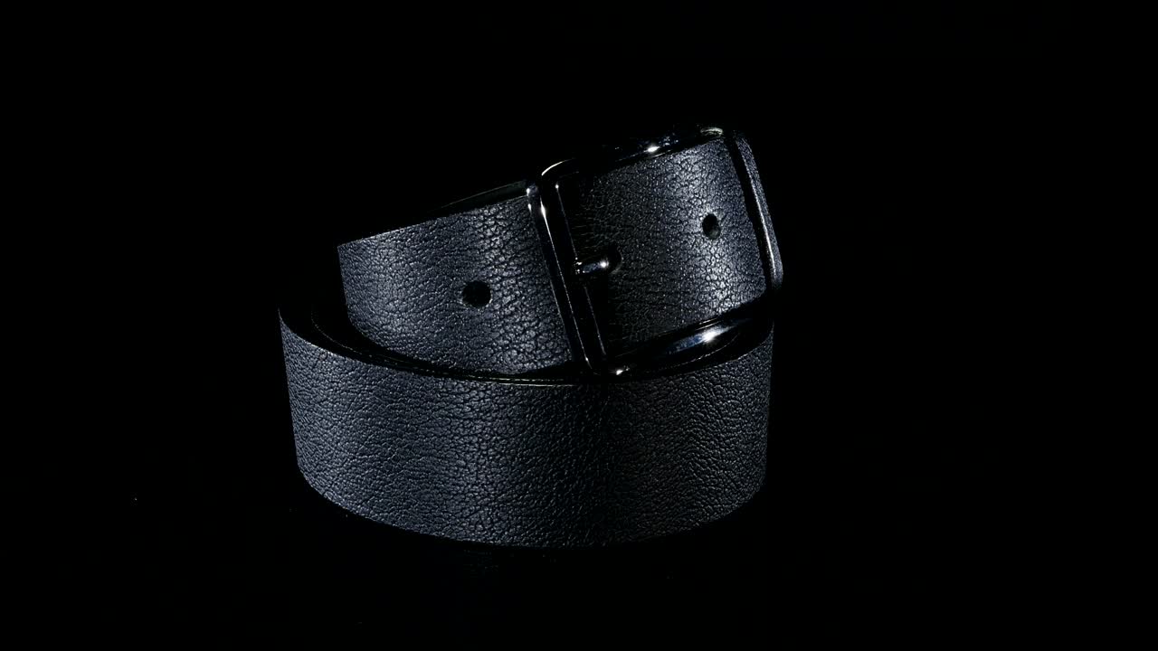 черный мужской пояс вращается на черном фоне