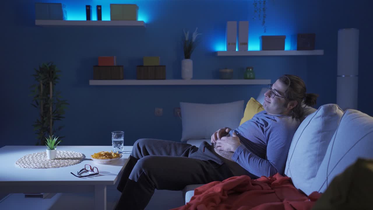 Uomo buffo che si gratta la pancia mentre guarda la TV.