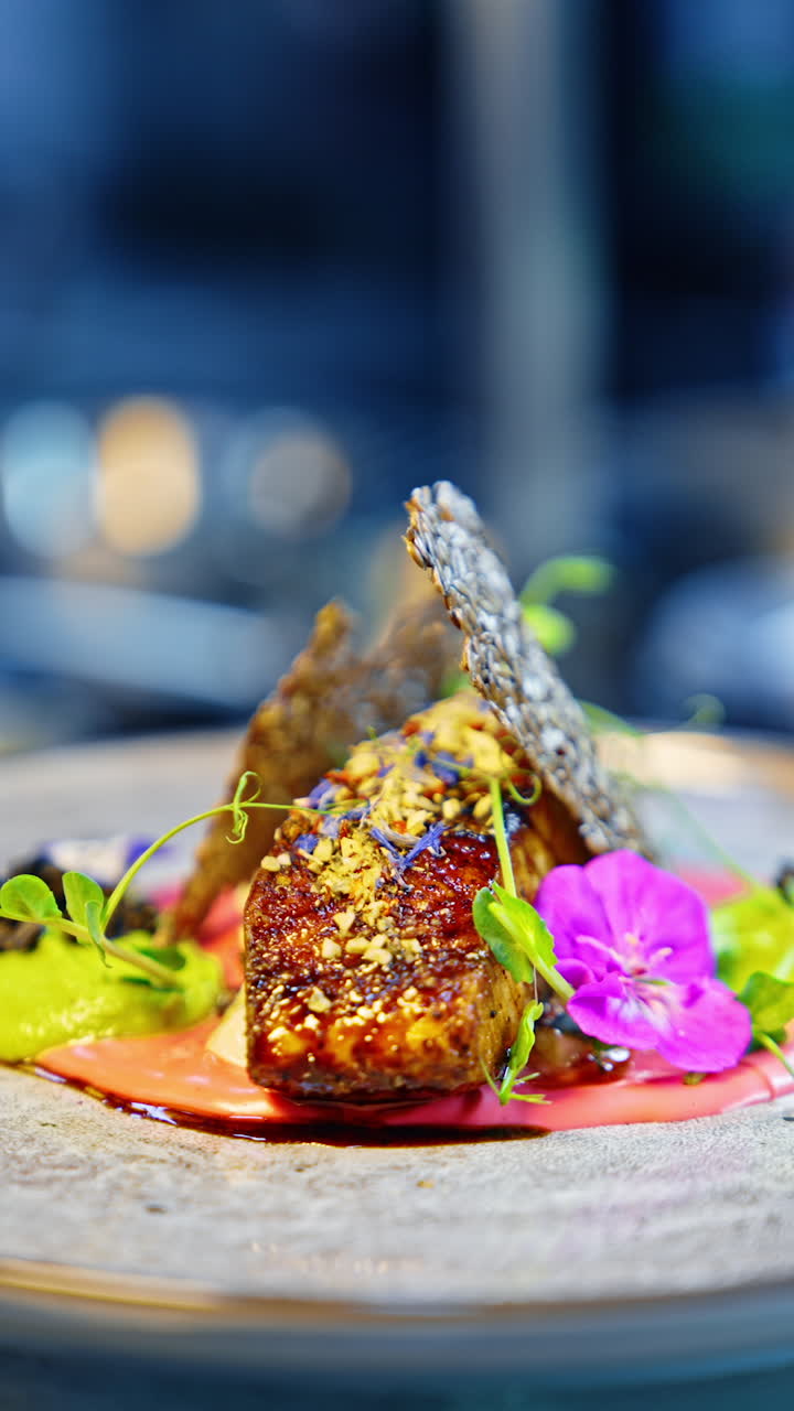 Beautiful serving of fried fish with seed crust, green sauce, microgreen, and flowers. Healthy and tasty food concept. Vertical video.