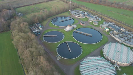 flying away from large water tanks on terrain of sewage water treatment plant