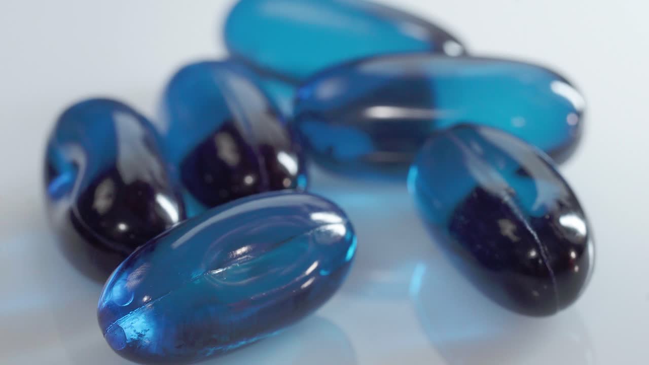 Close up of hand holding blue gel medicine capsules, healthcare product detail
