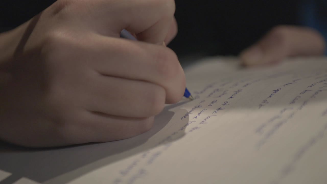 en person som sakte skriver på et hvitt papir ved hjelp av en blå ballpen