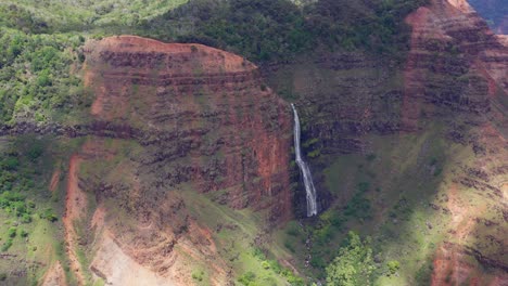 4k drone shot of the waipoo waterfall in waimea canyon state park. an 800 foot tall waterfall cascading down in two tiers into the lush green canyon below