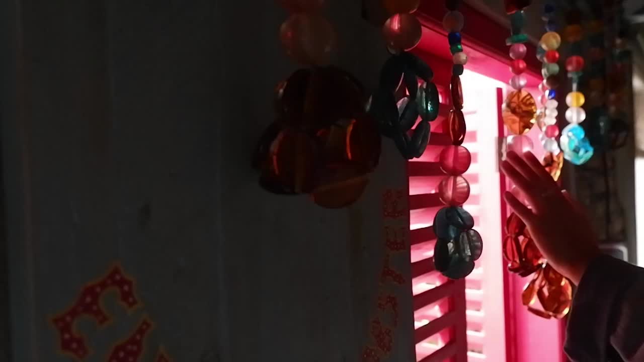 la mano toca la cortina de cuentas en la pared de la ventana