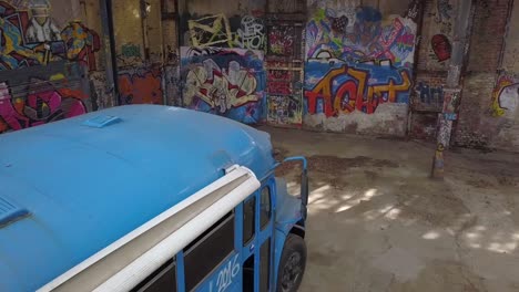 vuelo de drones sobre un autobús escolar azul en una fábrica abandonada con arte callejero de graffiti en las paredes