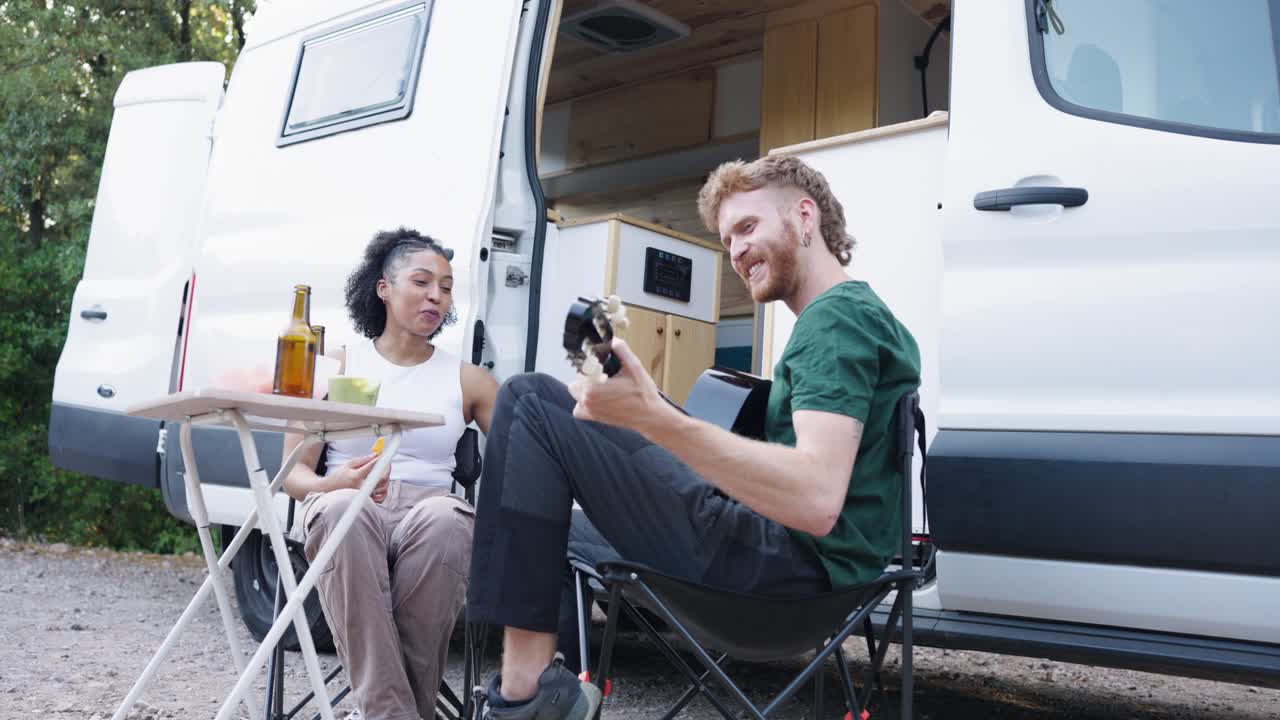 Couple enjoying van life with guitar and snacks