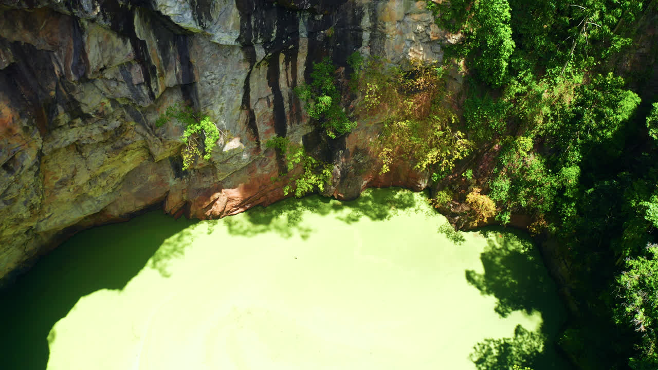 cráter del monte hypipamee con superficie de agua cubierta de hierba de pato, rodeada de paredes de granito y vegetación de selva tropical en australia