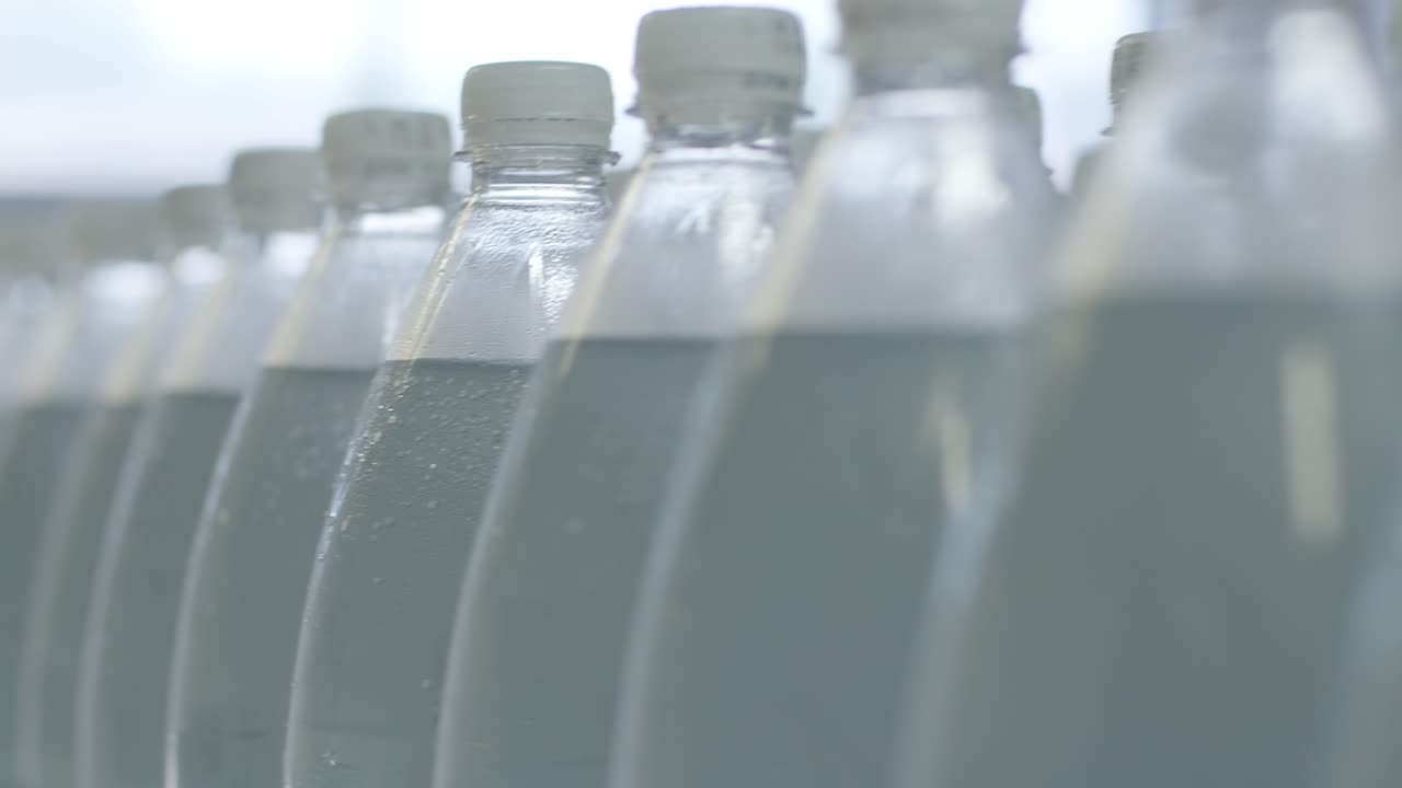 cinta transportadora con botellas de agua potable en una planta de bebidas moderna